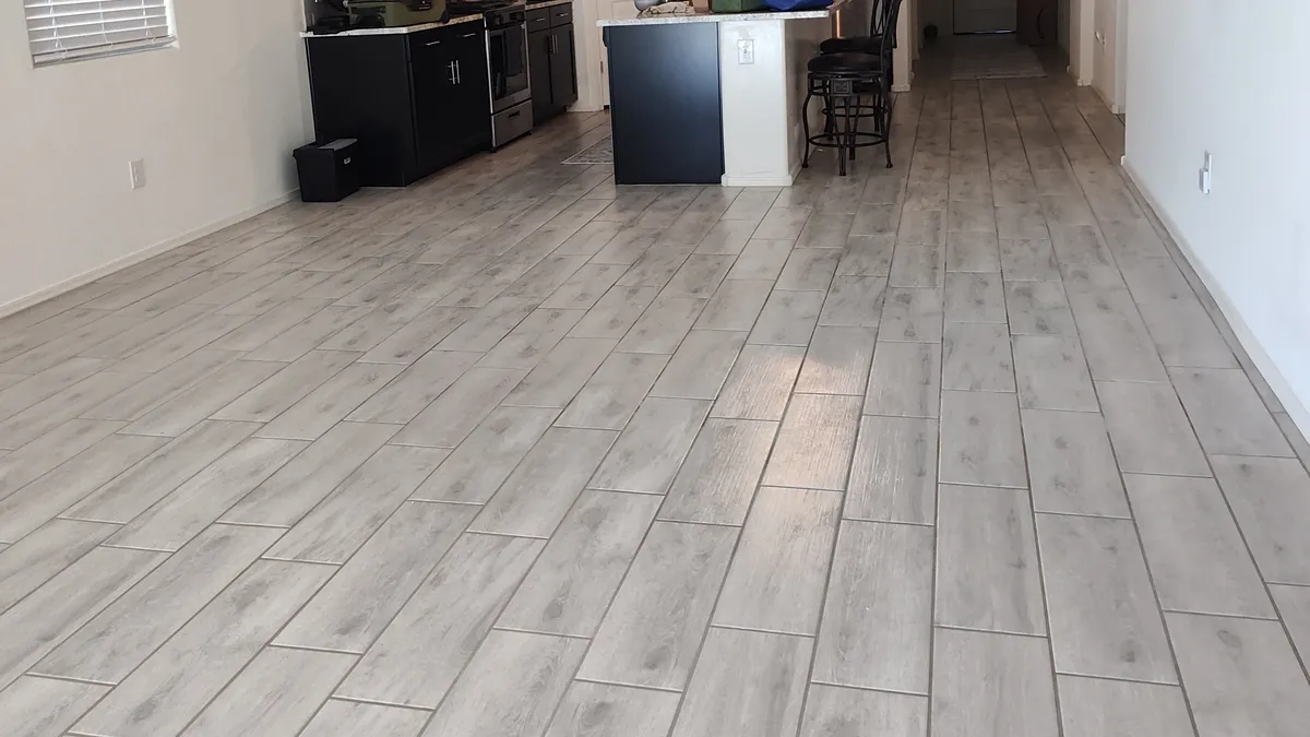 Long plank tile floor running through a clean, open kitchen and living area